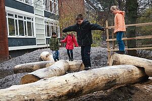 Kinder balancieren auf Holzstämmen im Freien