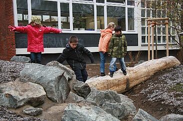 Wasserläufe_Wassermulden_Lernräume_außen Kinder balancieren auf Wasserläufen im Hof
