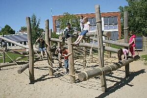 Kletterstruktur_Lernräume_außen Kinder balancieren auf einem Holzparcour