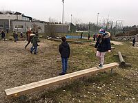 Kinder balancieren über Holzstange im Schulgarten