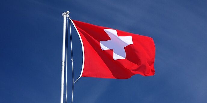 Schweizer Flagge mit blauem Himmel als Hintergrund