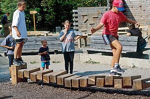 Kinder balancieren auf Hängebrücke aus Holz